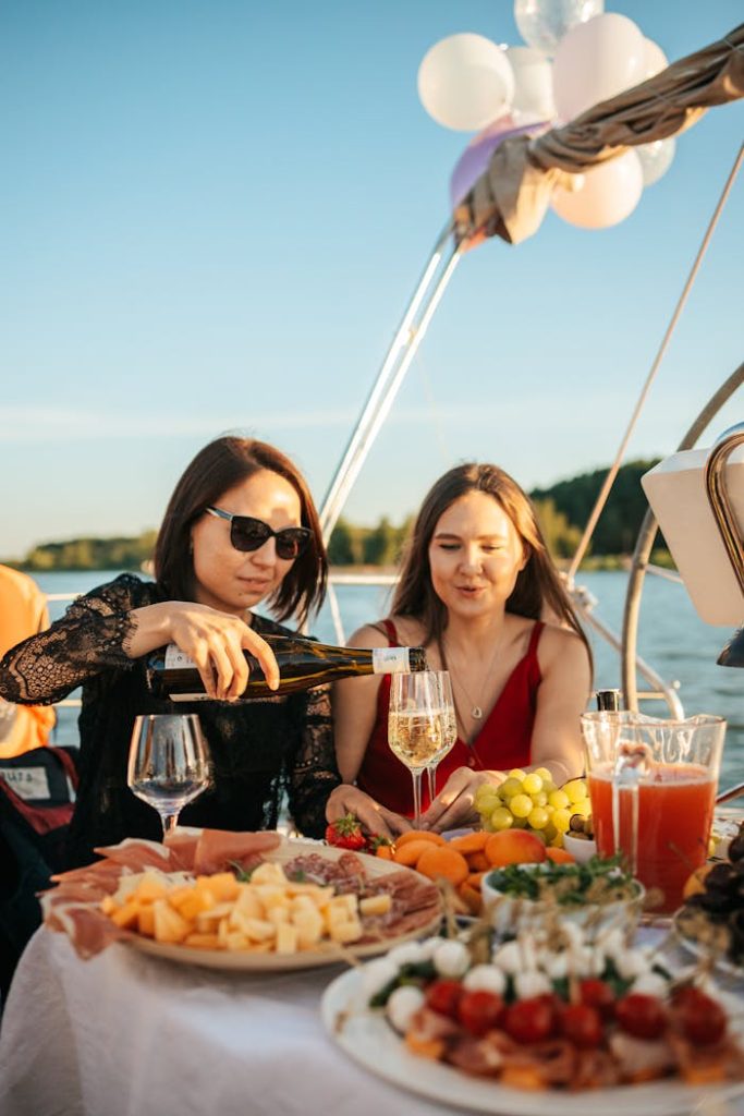 Women enjoying a yacht party with drinks and a variety of foods, creating a festive mood.
